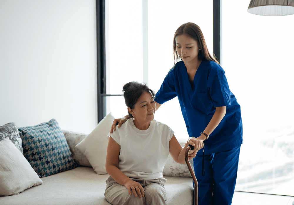 Caregiver assisting elderly woman with cane